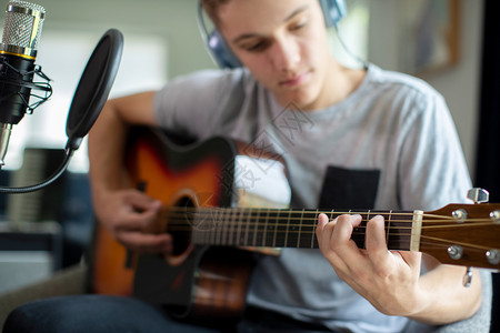 在家里玩吉他和录音乐的少年男孩麦克风人放大器图片