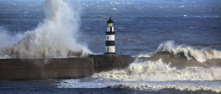 冬天王国超过英格兰东北海岸的汉灯塔上坠落的波浪高清图片