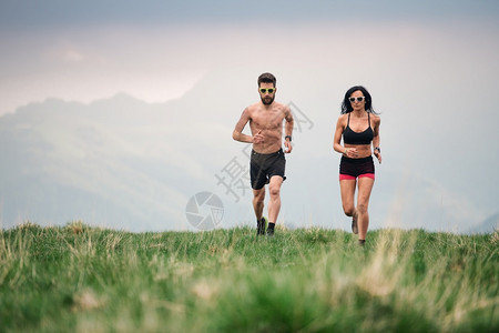 耐力夏天在山丘草原上男女运动的子和都跑得火热的上坡图片