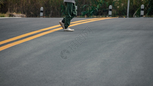 积极的穿着运动鞋男子在街上走着黄线脚丫子户外背景图片