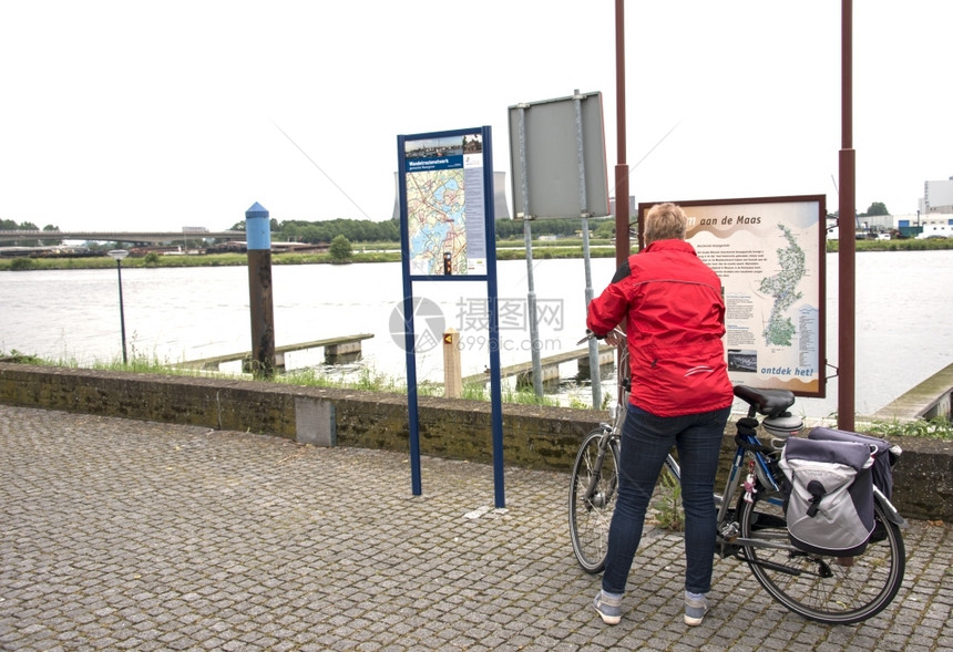 路线女人在荷兰的河马斯附近信息板上看旅行假期图片