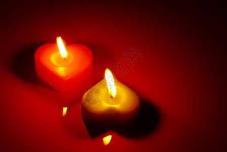 红桌上两个燃烧的心形蜡烛浪漫圣诞节红色图片