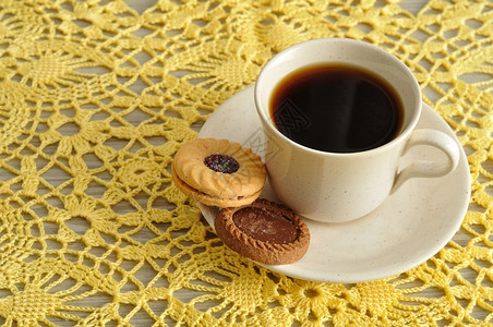 一个茶杯在编织布上展示圆饼干钩针编织种类棕色的图片