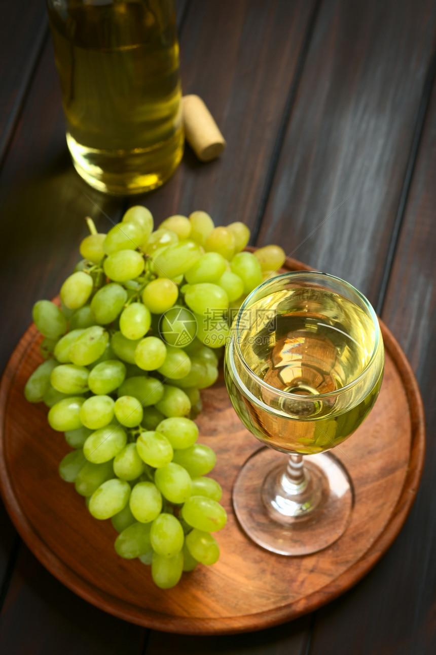 轮缘自然食物白葡萄和一瓶酒的白杯子用天然光聚焦点在暗木上拍照重点放在葡萄酒杯的前端以红酒杯前侧为焦点图片