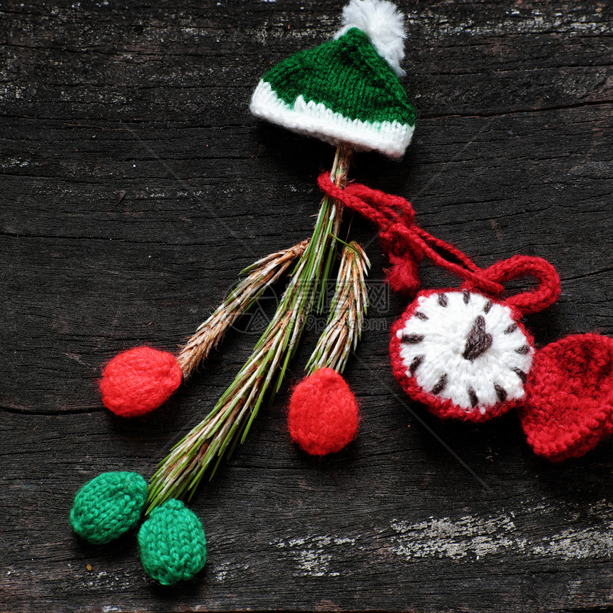圣诞节绿色小丑来自松树叶带编织的帽子和红钟在黑色木制背景针织图片