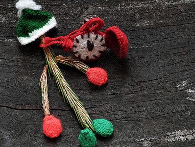 叶子针织的圣诞老人小丑来自松树叶带编织的帽子和红钟在黑色木制背景图片