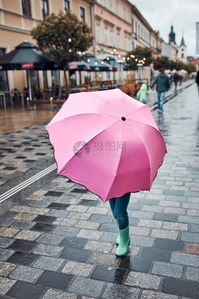 落下躲在粉红色大伞后的小女孩在阴雨沉的秋日在市中心散步走一种图片