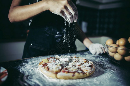 厨师在披萨上撒面粉背景图片