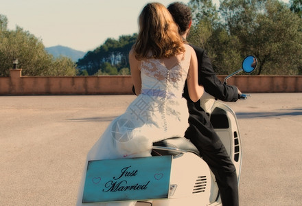 新婚夫妇驾摩托车离开婚礼时的摩托车离婚路美丽的愉快图片