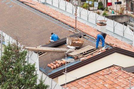 修理房顶小山村建筑屋顶大楼翻修的工人建筑房顶改造中的工人身体一种男人背景