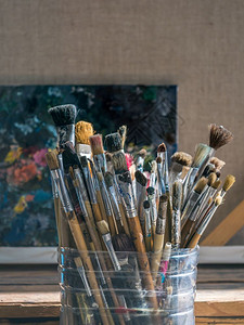 艺术家画工塑料桶中旧用过的油漆刷子旧用纸桶中过的油漆刷子底有色调盘和衬布的塑料桶背景图片
