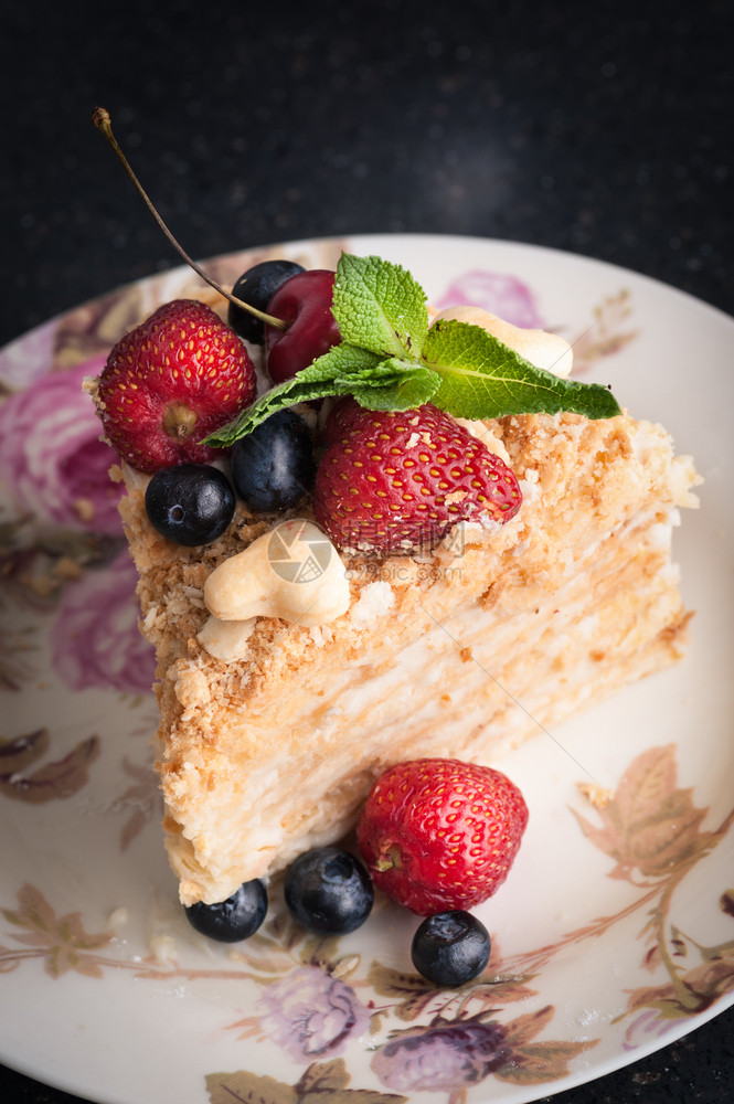 一小块蛋糕在盘子上加浆果的拿破仑甜点一种美味的图片
