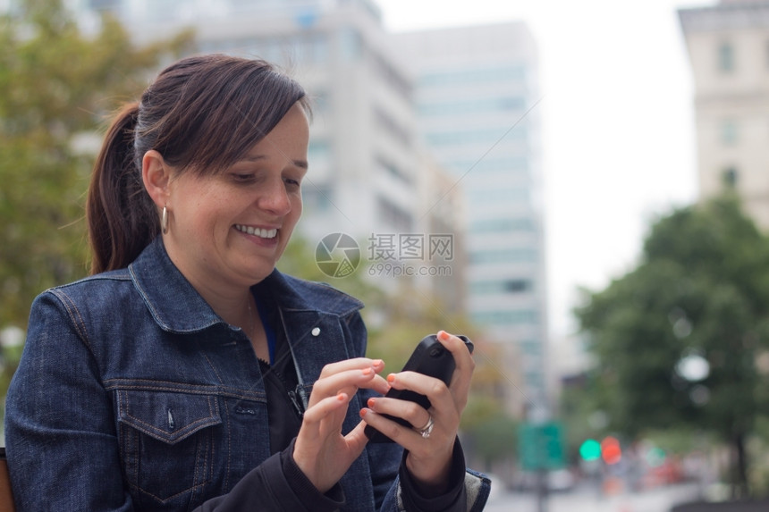 女用她的智能手机向外发短信部城市聪明的图片