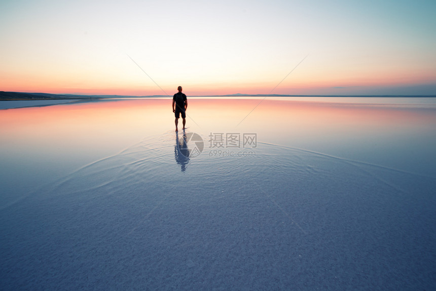 水盐海滩人在平静的湖面上进入日落的剪影隐私与和谐的概念人在平静的湖面上进入日落的剪影图片