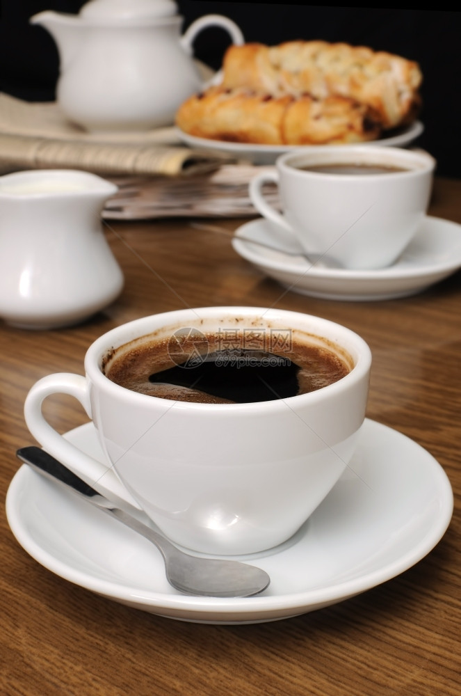 垫餐桌上加一杯黑咖啡奶工和饼干在报纸的盘子上托香料图片