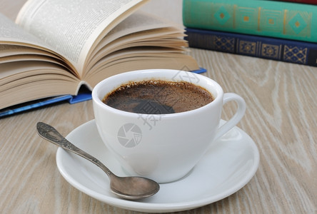 早餐杯子在一本公开书的背景之下桌上放着一杯咖啡香味黑因图片