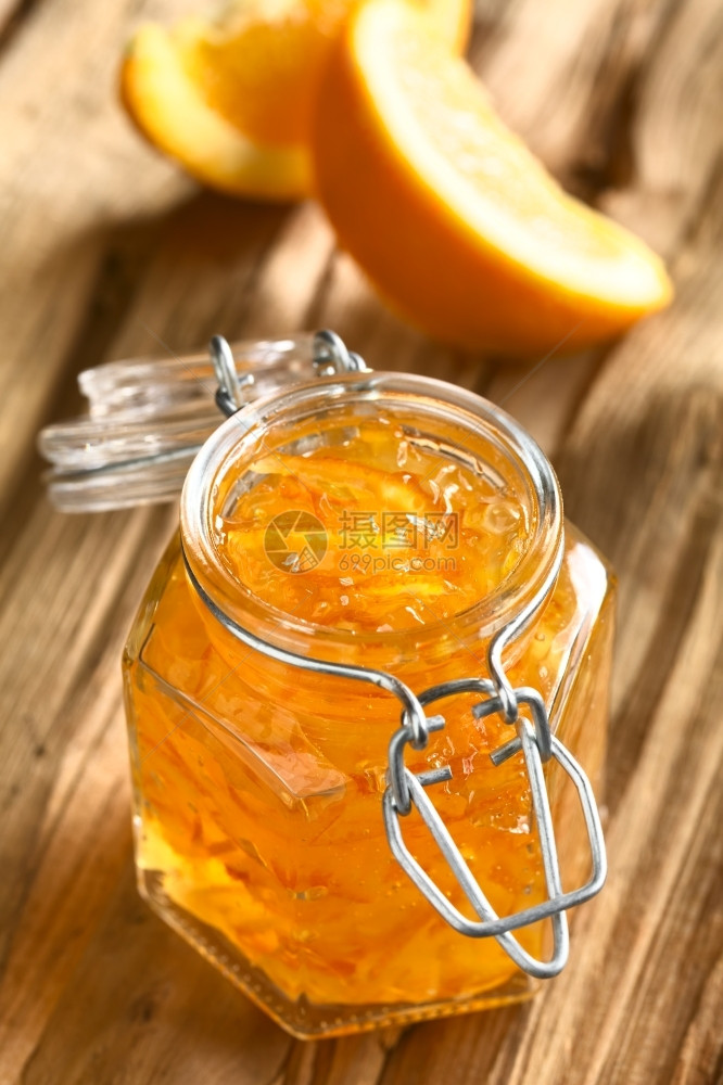 热情剥木头上摆顶加橙片的木头圆顶罐中橘子果酱与天然光选择焦点相拍摄聚于果酱上头两条橙子皮早餐图片