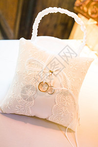 白色枕头上的两个金婚戒特写白色枕头上的两个结婚戒指特写金的象征爱背景图片