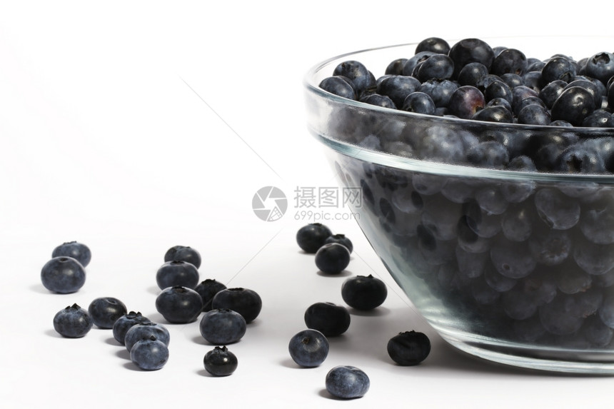 多汁的一种满碗蓝莓和一些空闲的碗还有很多蓝莓和一些在白背景上留下的蓝色浆果白图片