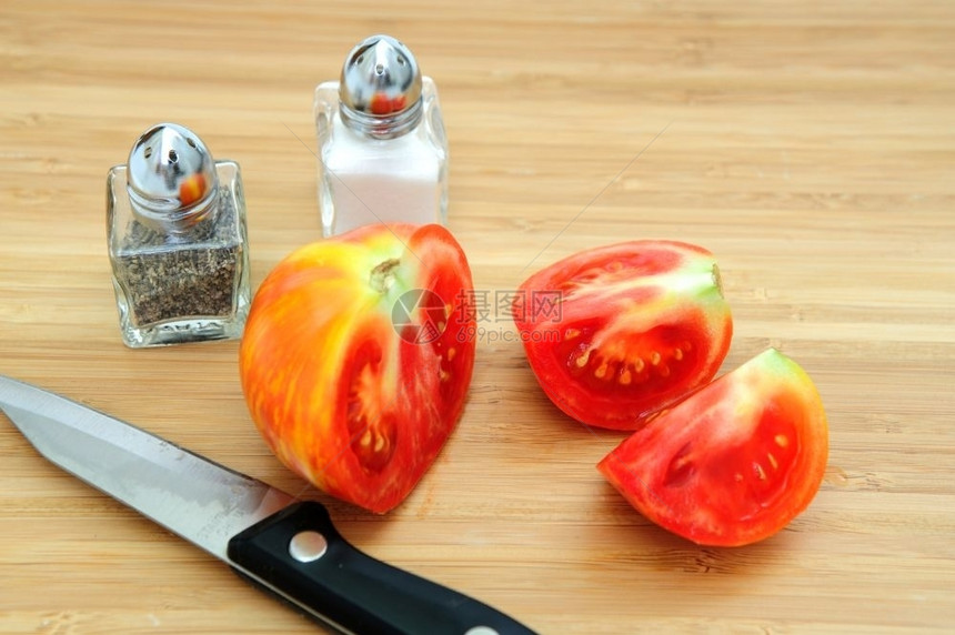 红黄双海鲜番茄在木板上切成织物用尖刀盐和辣椒搅拌机小刀和盐红色的食物木制图片