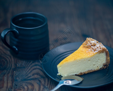 黑盘子和咖啡上的芝士蛋糕桌子木制的奶油图片