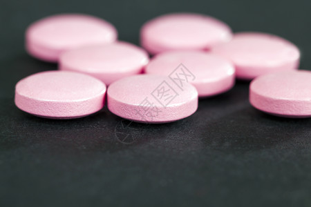 粉色药片粉红药片躺在一张黑纸背景上检查用于治疗病症的药剂黑粉色品花园的关心背景