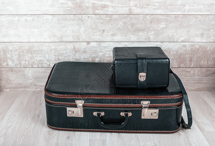 行李过时的一堆两个老式黑色皮箱放在木质背景上两个老式黑色手提箱处理图片