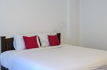 早晨木制的白色卧室有整洁的国王床和红色枕头公寓图片