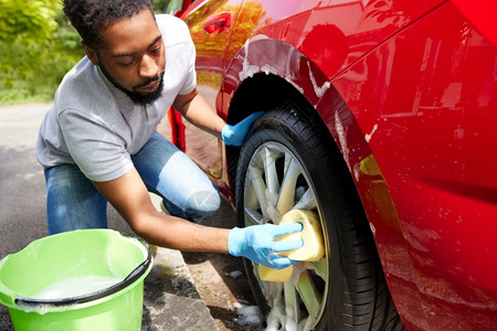 职业洗涤男人使用巴奇和海绵的代言人期间男子洗车轮背景图片