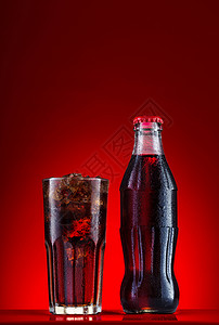 红底黄字碳酸化的苏打棕色瓶中碳酸饮料瓶中一杯含冰的玻璃红底面上有冰杯中含碳饮料加冰设计图片