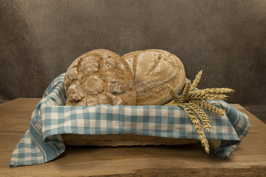 拼写可口木制的两块新鲜烤面包放在篮子中一里有两块面包另一篮子里有个蓝色和白的餐桌面包布二放在篮子中图片