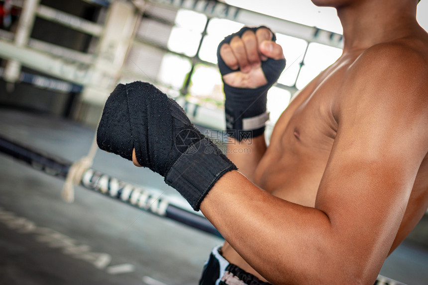 强的美丽男子拳击手在竞技场运动中用手包着他的身体图片