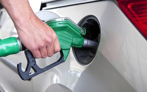 汽油车站柴机手加为一辆客车加油持有绿色燃料泵图片