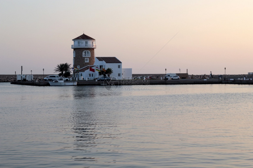 日落时地中海岸的灯塔上有一个小度假镇入口处前往西班牙阿尔梅里马港海滨建筑学假期图片