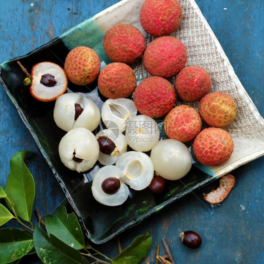 吃多汁的越南蓝色背景紧贴水果盘子利奇或赖谢水果VaiThieu红果皮白纸浆甜和美味图片