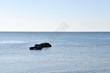 平静蓝水中的黑石海景平静云图片