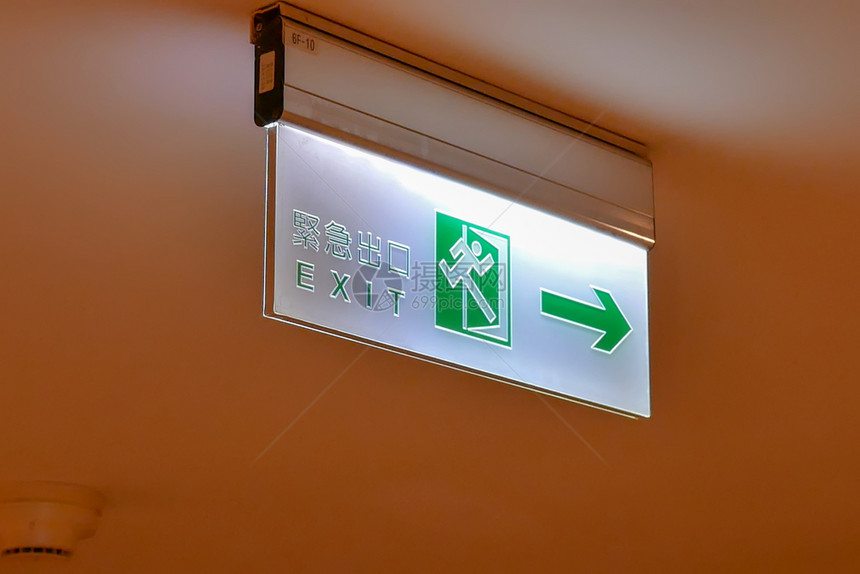 英语在商场的天花板上用中文和英字写出紧急口标志贴近紧急出口标志定向的箭图片