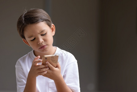 儿童一脸疑惑的玩着手机图片