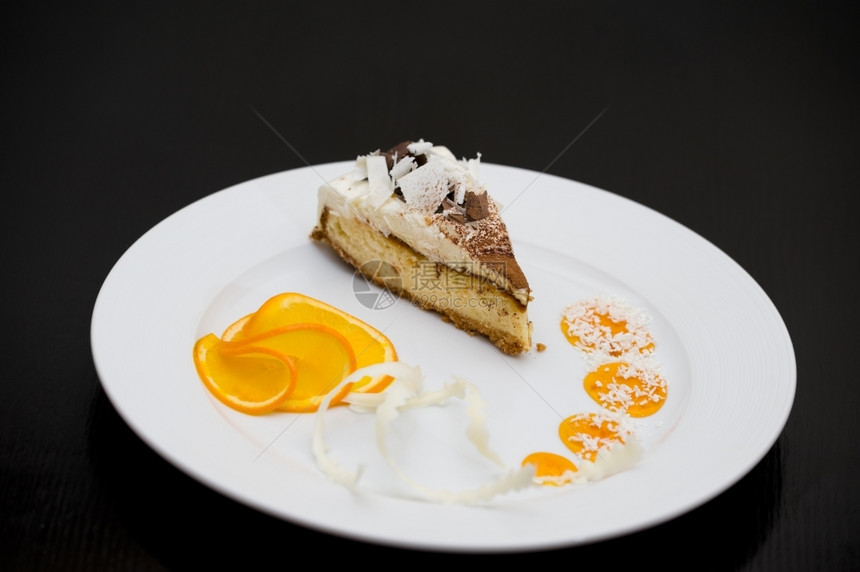 甜的一块带白巧克力和黑的海绵蛋糕配有橙色切片和糖浆场地波德希瓦洛夫图片