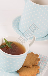 玻璃热有薄荷饼干的茶放在瓷杯和碟子里木制的图片