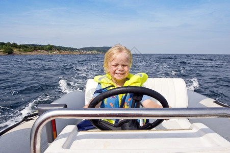 海年轻男孩驾驶着一艘充气快艇的方向盘喜悦生活图片