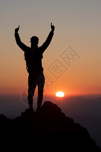 获胜运动登山者在日落时高峰会太阳背景图片