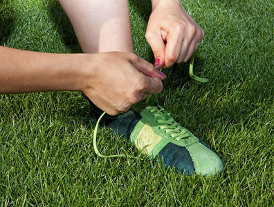 健康训练女子在运动鞋上系带身体的图片