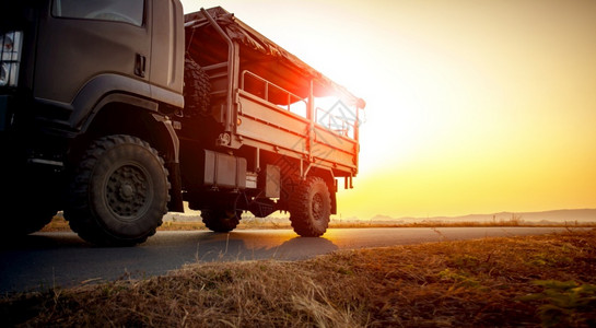 土地维护晚上军用卡车在沥青高速公路上行驶对抗美丽的日落天空图片