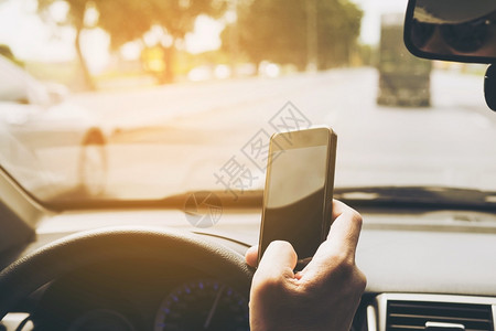 窗户近距离接一个男子使用移动电话危险驾驶汽车的人和眼镜危险的图片