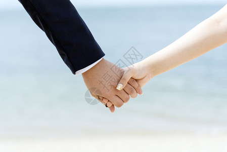 相爱的年轻情侣在海滩牵手特写图片