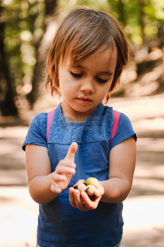 金发小女孩手上拿着橡子的小桃用背包在森林的路上冒险外部青年图片