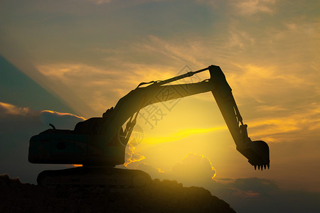 挖掘机在日落的天空上努力工作量铲土方图片