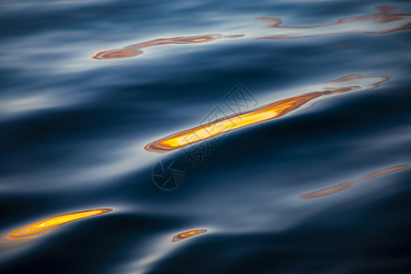 自然波在深水中以金色和黄反映光亮海浪有色束背景图片