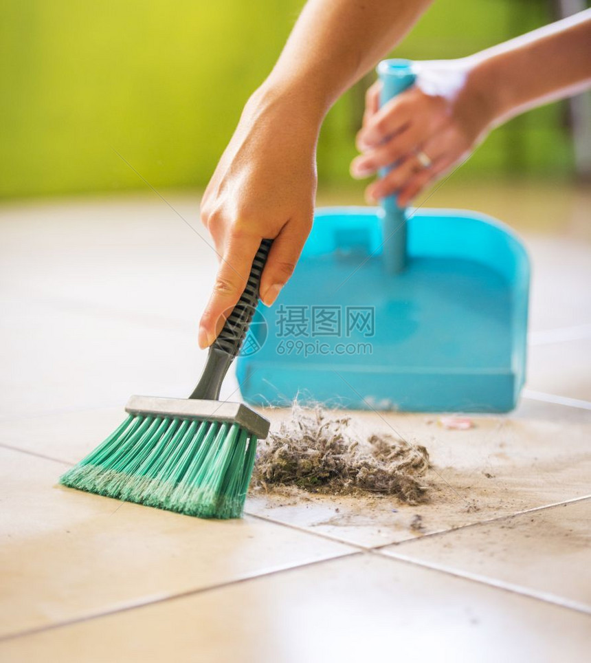 蓝色的一个女人在清扫房屋时从地板上扫灰尘和泥土棕色的图片